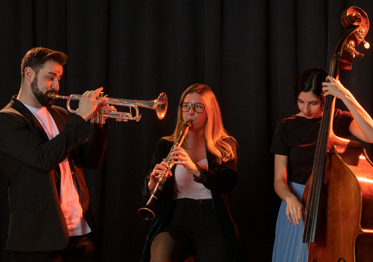 Tecnología para la Vida TXLV - MicroMagazine de FUNTESO, Fundación Tecnología Social imagen de un escenario en el que destaca una cortina roja de teatro, varias personas sentadas en sus butacas de espalda y varios focos, además de un equipo musical